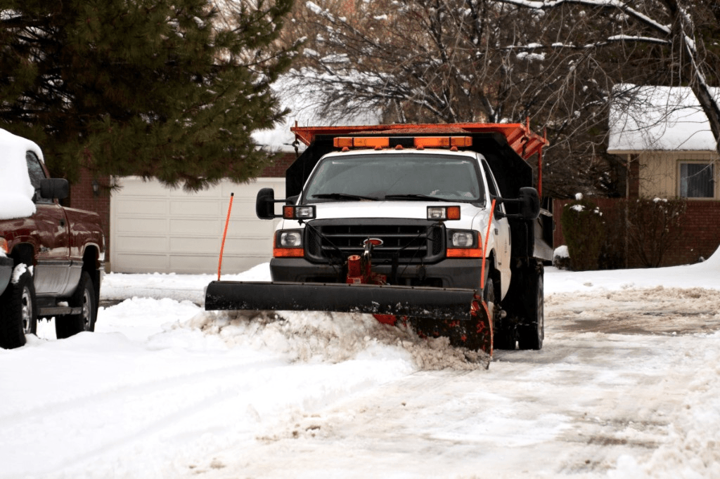Truck with plow clearing snow from a residential street